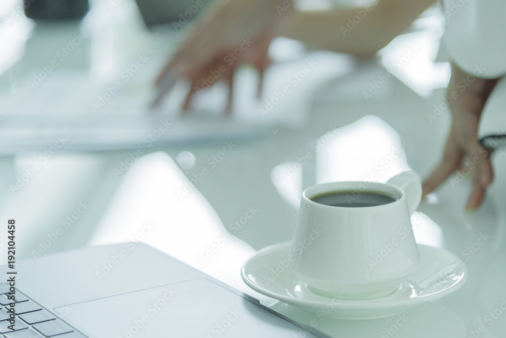 A coffee cup with white plate on the office desk. A coffee cup with white plate on the office desk.