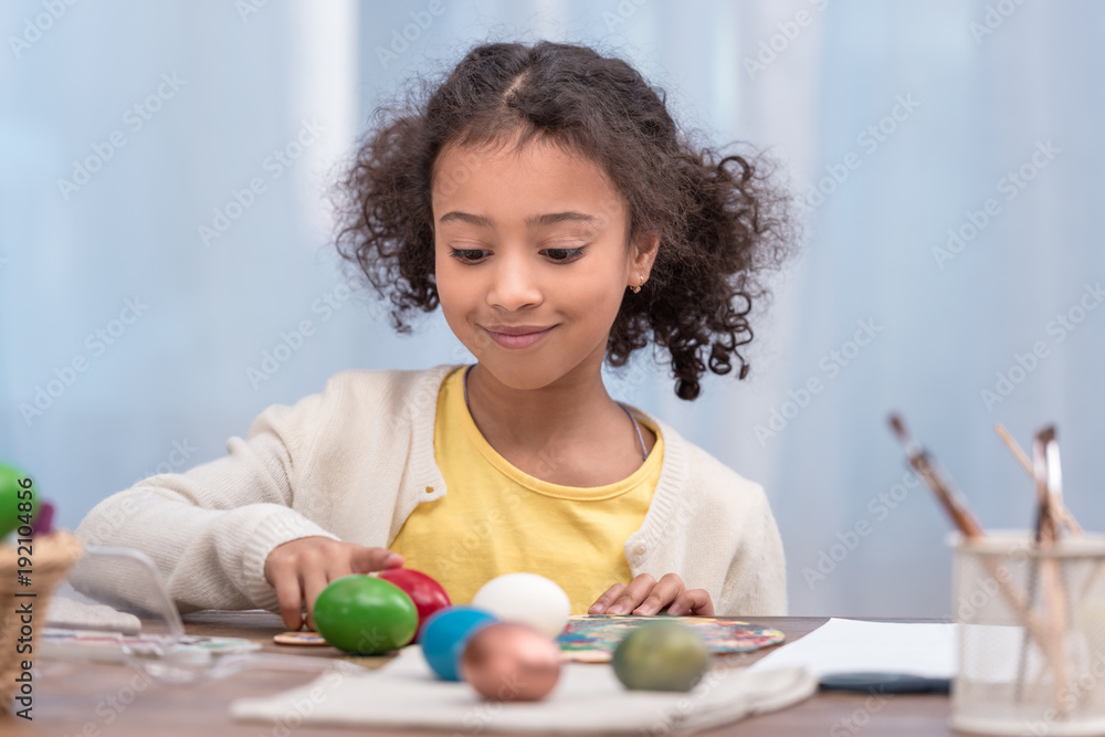 Fototapeta premium adorable african american kid playing with painted easter eggs