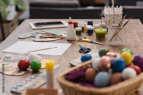 painted easter eggs and tools for painting on wooden table
