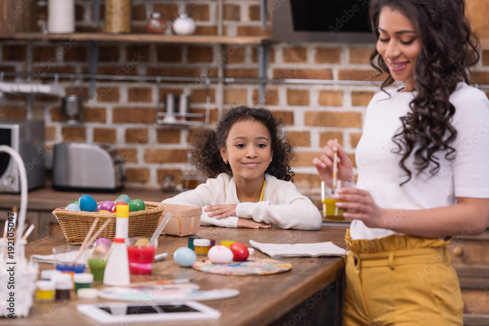 african american daughter looking at mother making paint for easter eggs african american daughter looking at mother making paint for easter eggs