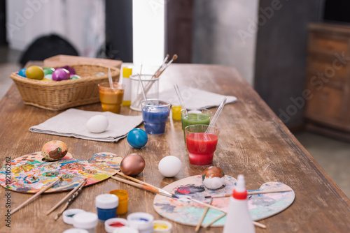 painted eggs with paints and brushes on wooden table, easter concept