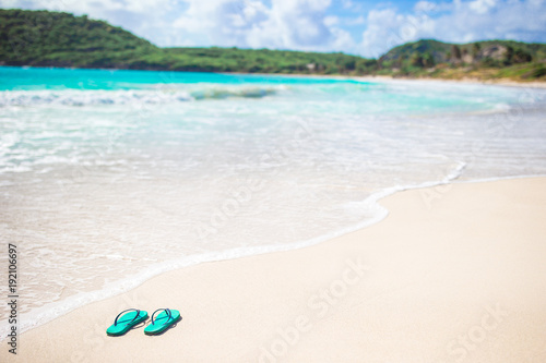 Bright flip-flops on a white beach with white sand, turquoise ocean water
