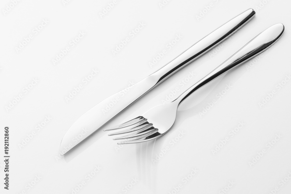 view of nice chromed utensils interlacing on white sheet view of nice chromed utensils interlacing on white sheet