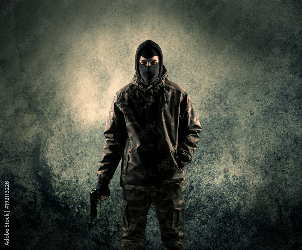 Portrait of a heavily armed masked soldier with grungy background
