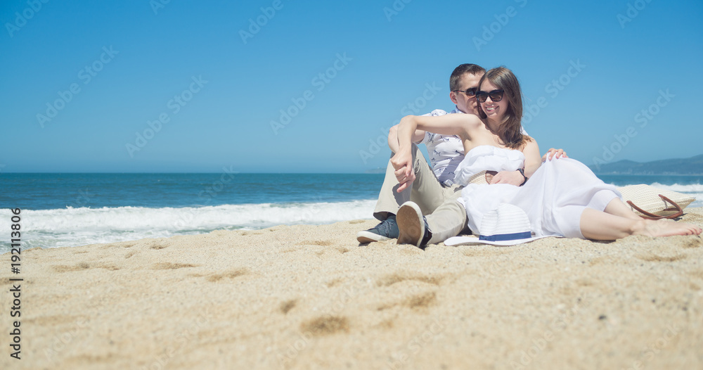 Young smiling couple sitting on the beach