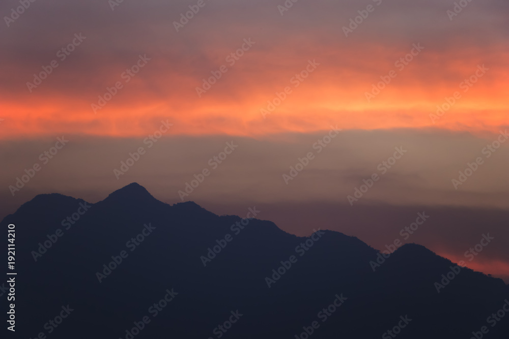 silhouetted sunset sky with the mountains.beautiful orange clouds after sunset for background