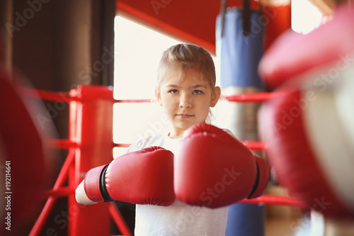 Little girl in boxing gloves on ring
