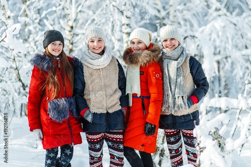 Beautiful teenage girls having fun outside in a wood with snow in winter on a wonderful frosty sunny day. Friendship and active life consept