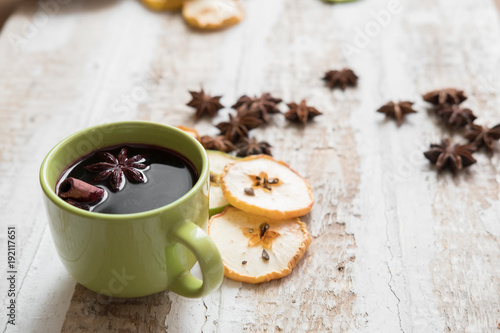 mulled wine in a green Cup scattered slices of dried apples and anise stars  toned background design