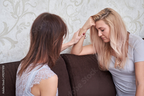 sad woman has problem, other woman consoling her at sofa in home photo