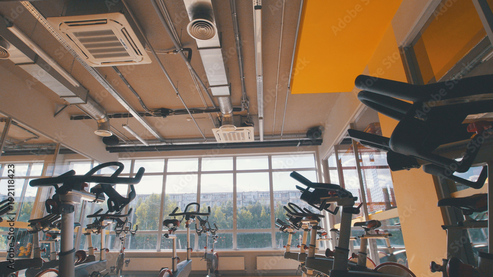 Fototapeta premium Bicycling simulators in the gym, interior of modern fitness club