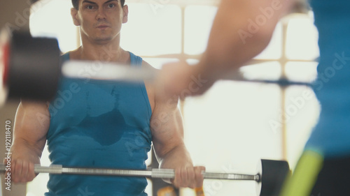 Bodybuilding in the gym - muscular man training his biceps near mirror