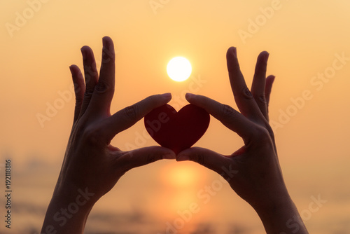 Close up and Silhouette of hand holding red heart during sunset background. Happy, Love, Valentine's day idea, sign, symbol, concept.