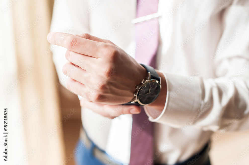 A man in a white shirt adjusts his watch A man in a white shirt adjusts his watch
