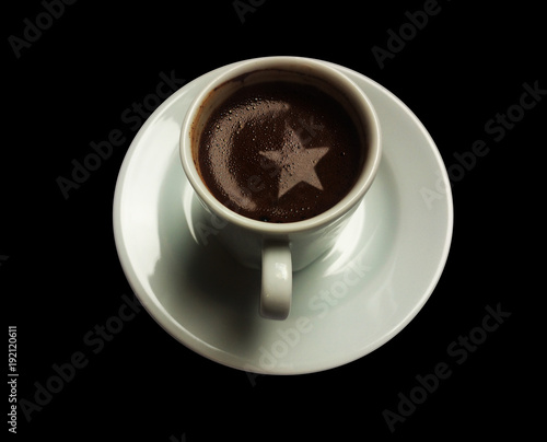 A cup of Turkish coffee with a crescent and star shape of the foam on isolated black background