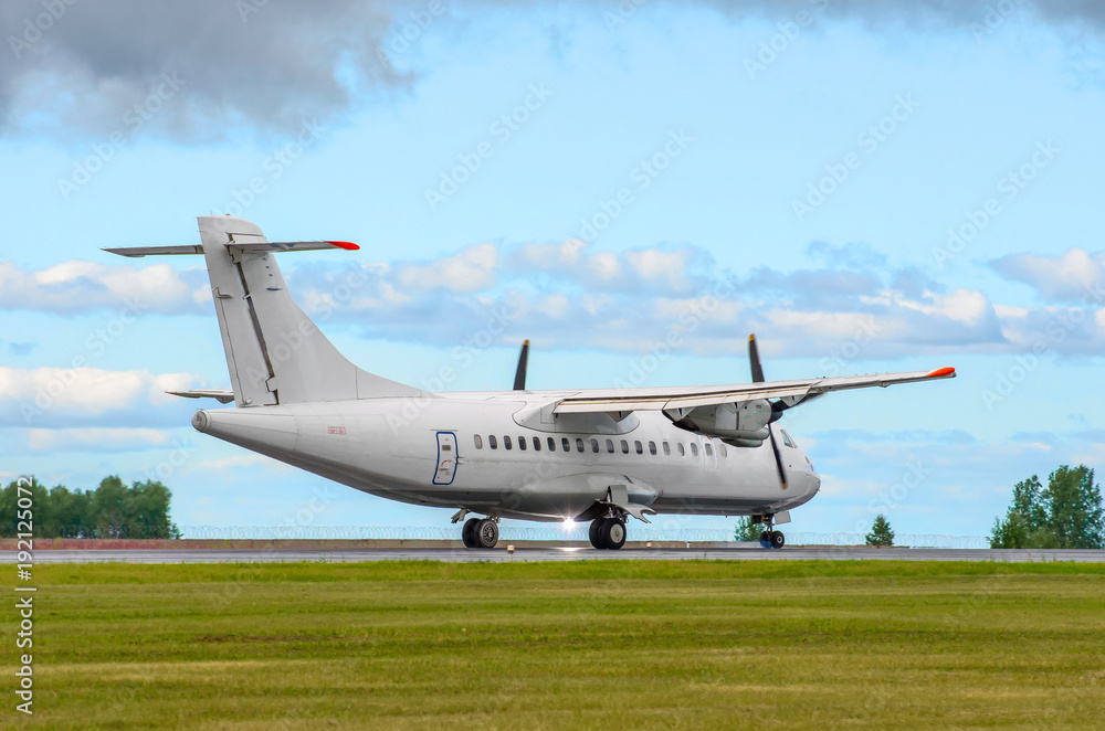 Passenger turboprop airplane landing the runway against the blue sky. Passenger turboprop airplane landing the runway against the blue sky.