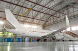 Passenger airplane in the hangar, enclosed engines and gangway at the entrance to the aircraft.