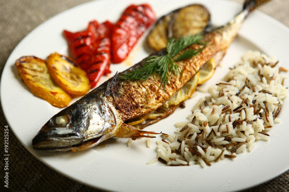 Healthy and proper food, grilled fish and vegetables with lemon and black and white rice on a white plate. Against the background of sacking and a wooden table. Low-calorie food Healthy and proper food, grilled fish and vegetables with lemon and black and white rice on a white plate. Against the background of sacking and a wooden table. Low-calorie food
