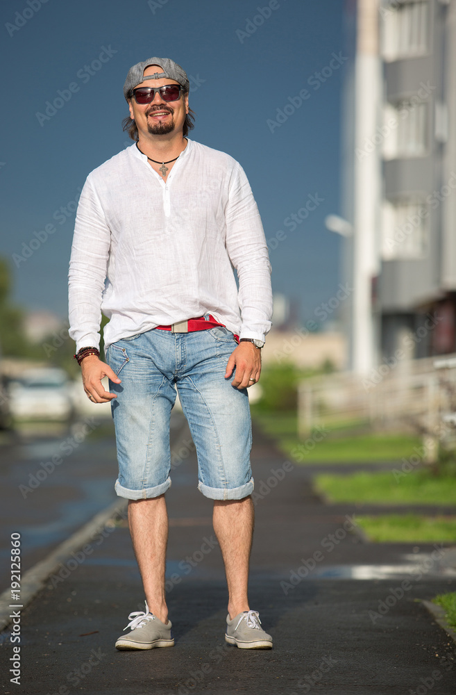 A man is walking in the courtyard on a sunny day. Lifestyle, movement, style, fashion. A man is walking in the courtyard on a sunny day. Lifestyle, movement, style, fashion.