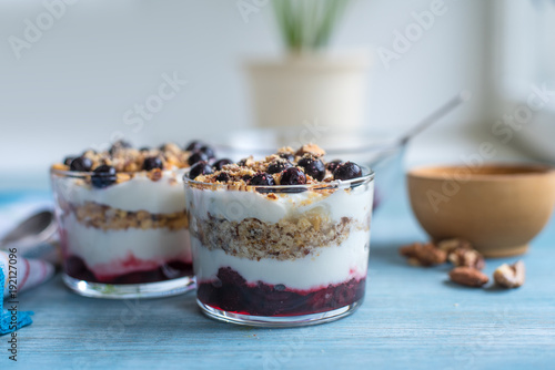 Delicious dessert - yogurt parfait with jam, nuts and currants in a glass