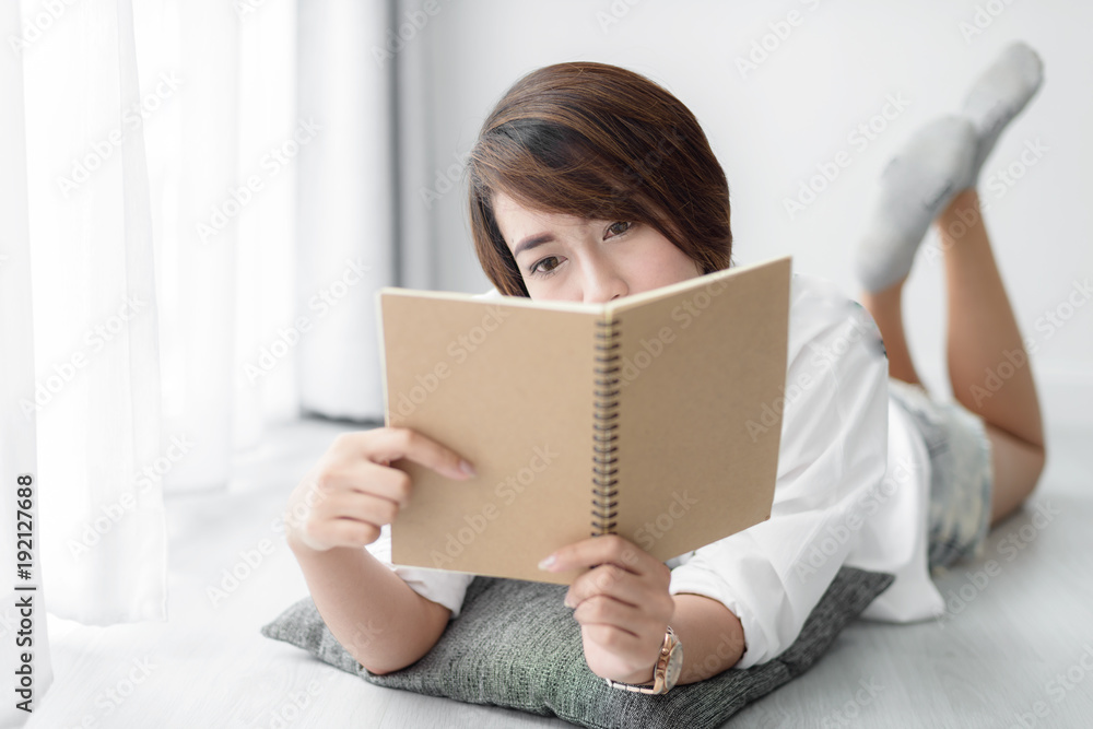 Beautiful woman laying down on floor and reading a book at home. Beautiful woman laying down on floor and reading a book at home.