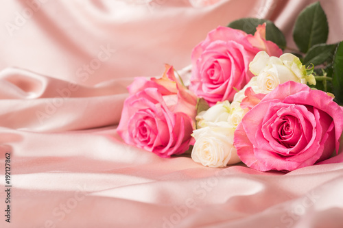 A bouquet of fresh roses on a background of a delicate pink satin. Copy space.Holiday concept. Selective focus.