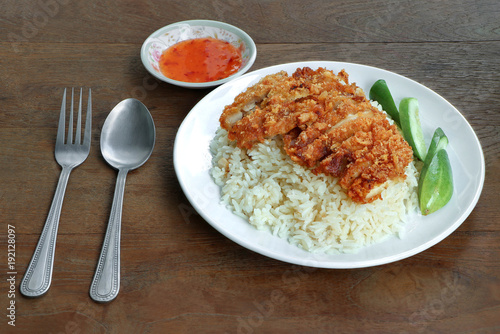 Fry chicken and rice in white dish with sweet sauce on wood table background.