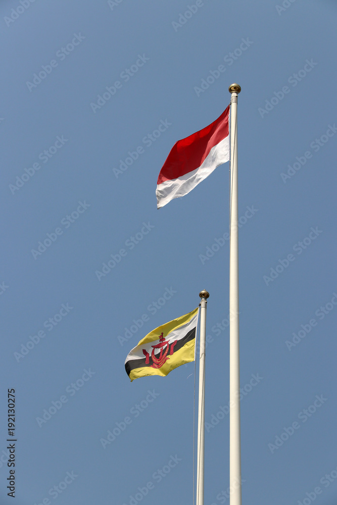 National flag of Brunei and Indonesia on bright blue sky background. Blown away by wind. Its are two of the ten Association of South East Asian Nations. The concept of bilateral or relationship.