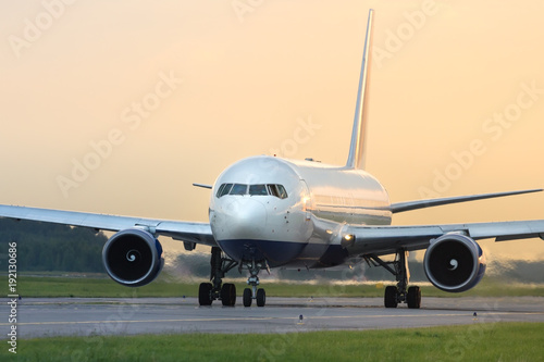 Close up of wide-body passenger plane taxing on the runway, during sunset/ Airplane turns on runway/ Very hot air behind the aircraft engine/Travel, summer vacation, transportation, aviation - concept