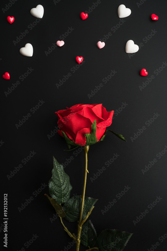 Obraz premium Flat view of red rose with valentines hearts and decoration on dark background with copy space. Symbol of love. Happy Valentines Day background.Saint Valentine's Day concept.