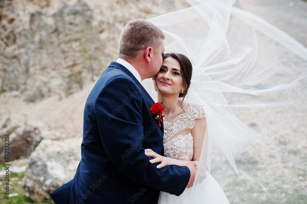 Romantic newly married couple posing and walking in rocky countryside on their wedding day.