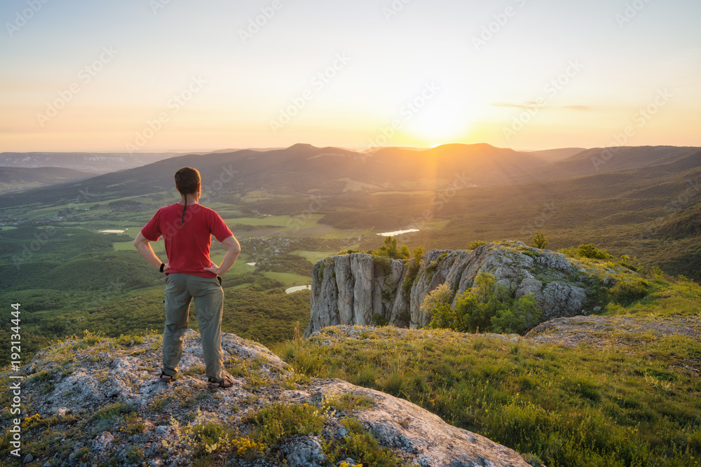 Human standing on a rocky hill in a light of sunset Human standing on a rocky hill in a light of sunset