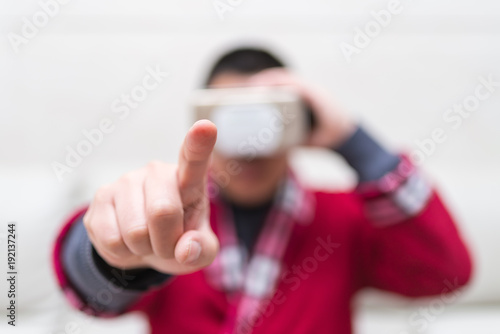 man wearing VR Glasses or Virtual Reality headset with his finger feeling the simulation world at home selective focus