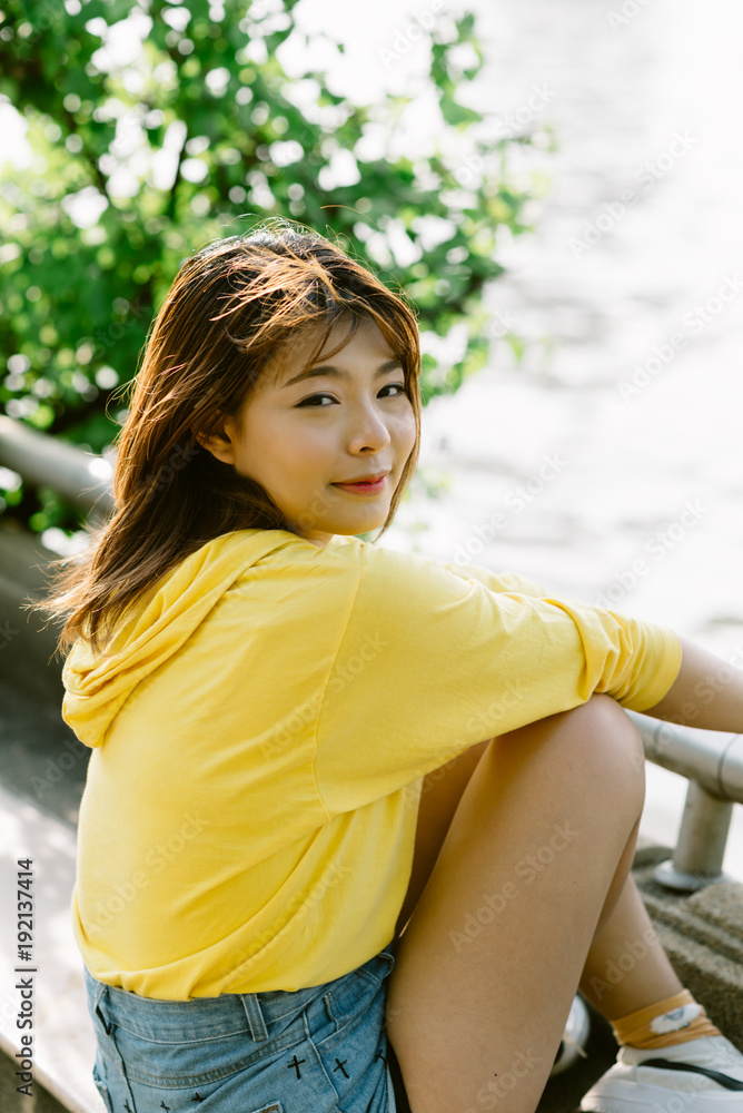 Lifestyle series: Young Asian woman in summer park by the river Lifestyle series: Young Asian woman in summer park by the river