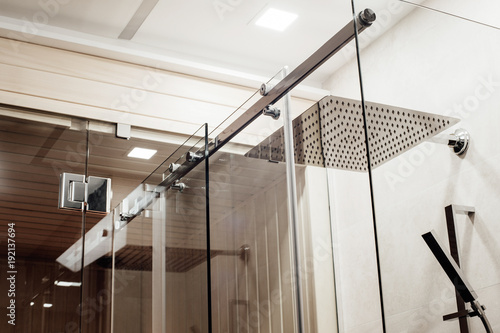 Metal structure of the upper fasteners and rollers for the sliding glass door in the shower enclosure conjugated with the glass door to the sauna view in the interior