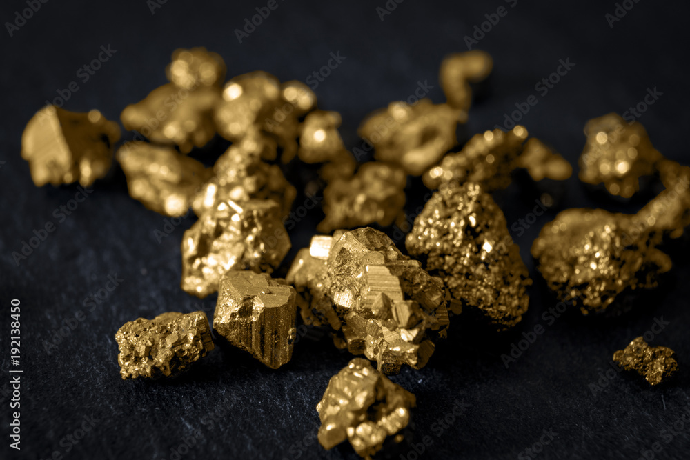Gold mining and and investment in precious metals concept with close up on golden nuggets on a black background