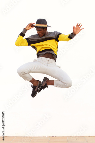 stylish young male dancer jumping and showing his moves on white background