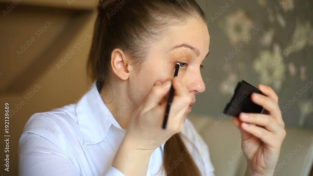 business woman paints eyebrows and eyes. Makes makeup in the morning before work business woman paints eyebrows and eyes. Makes makeup in the morning before work