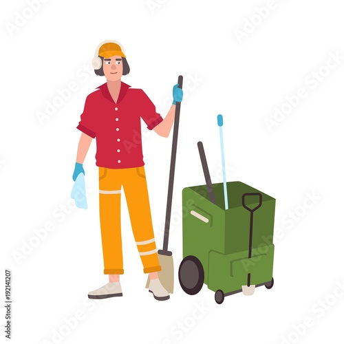 Young man wearing headphones and uniform standing beside mop bucket cart and holding broom