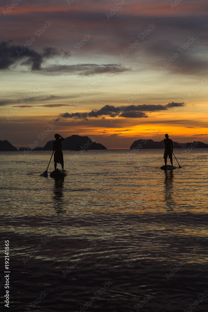 two man silhouette standing on sup boards on sunset time in El Nido, Palawan, Philippines, Corong Corong beach