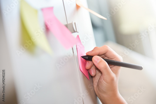female hand writing on post it notes.