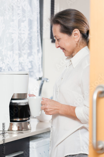  mature woman preparing coffee