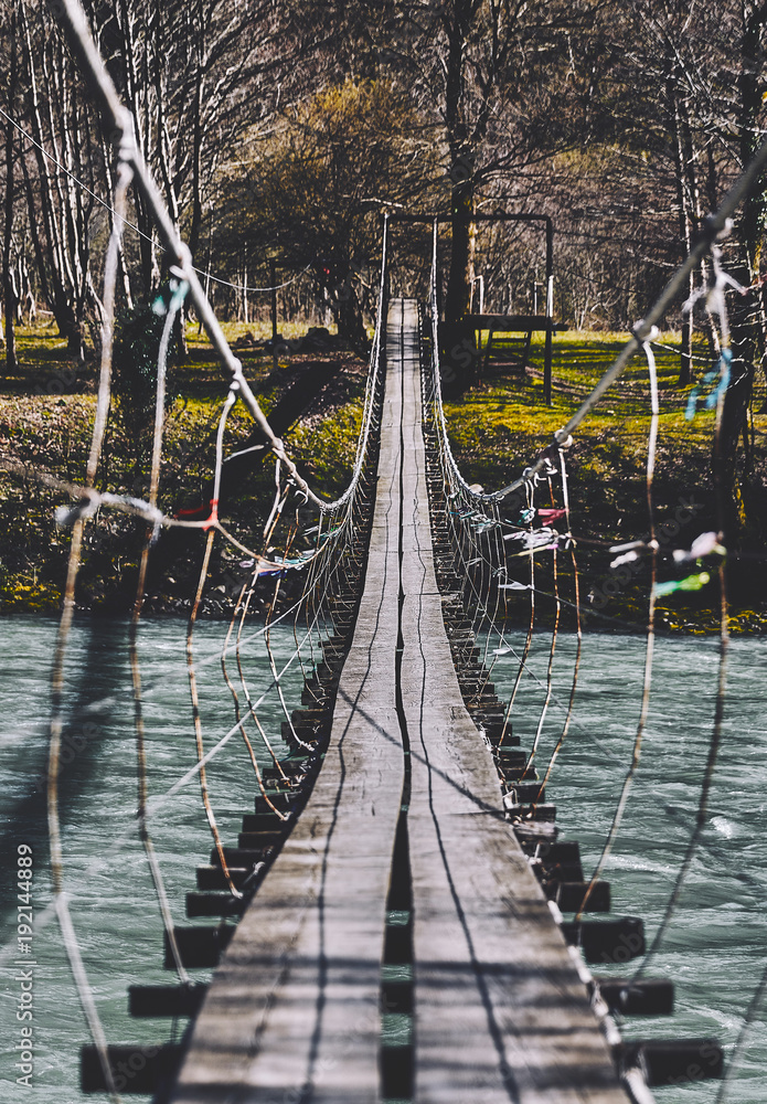 Fototapeta premium Beginning of an adventure, road into the jungle. Suspension bridge. Landscape view of Long Steel Suspension bridge above the river. balance