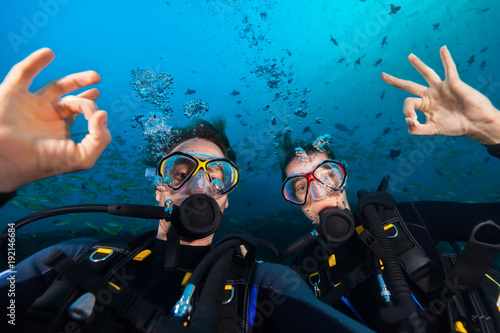 Couple of scuba divers showing ok sign, portrait photography