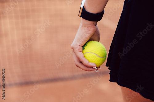 Woman holding tennis ball standing on the court. Close-up picture.