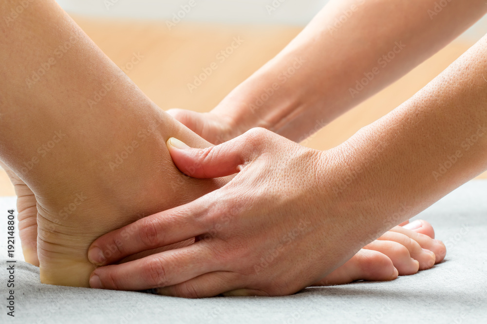 Therapist applying pressure on neuro emotional area on female ankle. Therapist applying pressure on neuro emotional area on female ankle.
