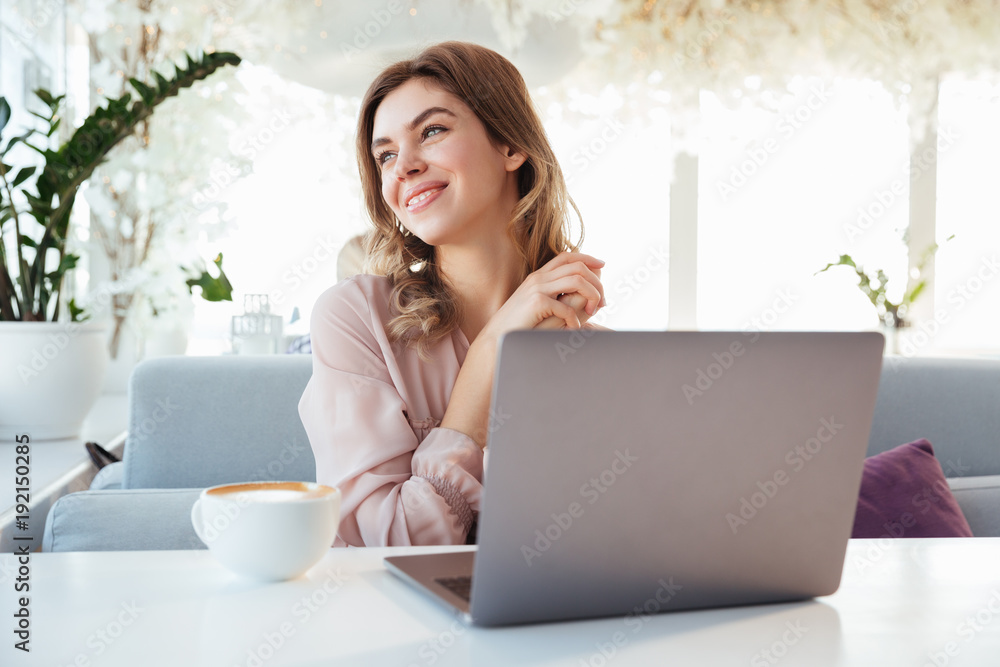 Portrait of a cheery young woman sitting with laptop computer Portrait of a cheery young woman sitting with laptop computer