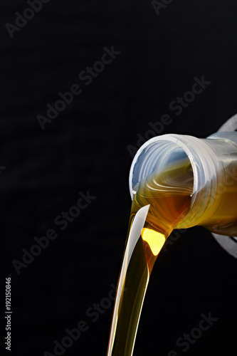 Pouring synthetic oils for car engine on a dark background.