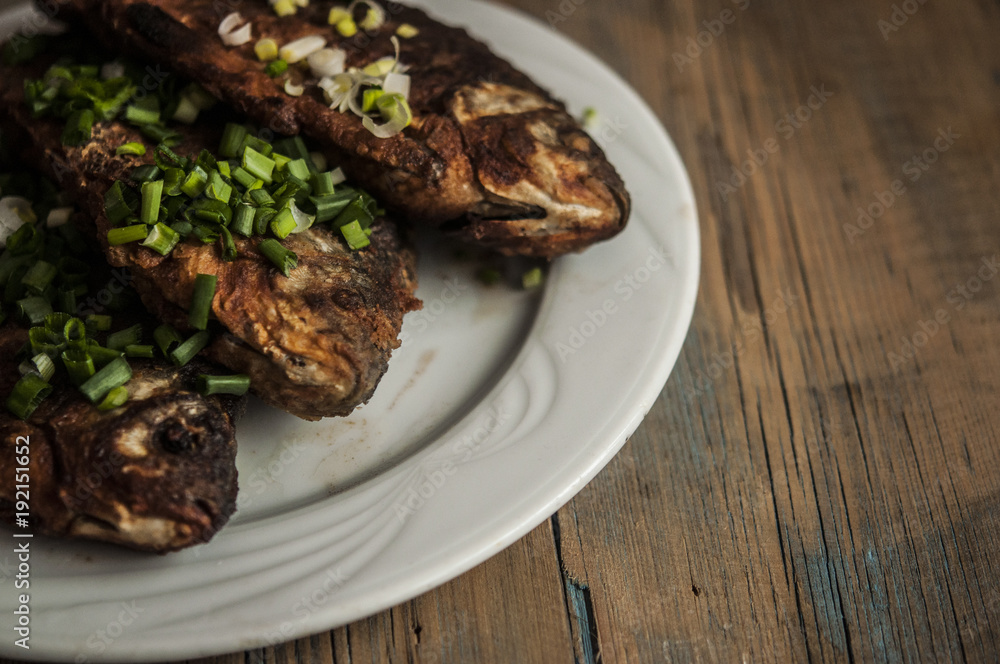 Fried fish crucian in plate on wooden table