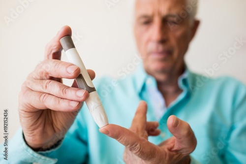 Senior man holding a blood glucose monitor photo